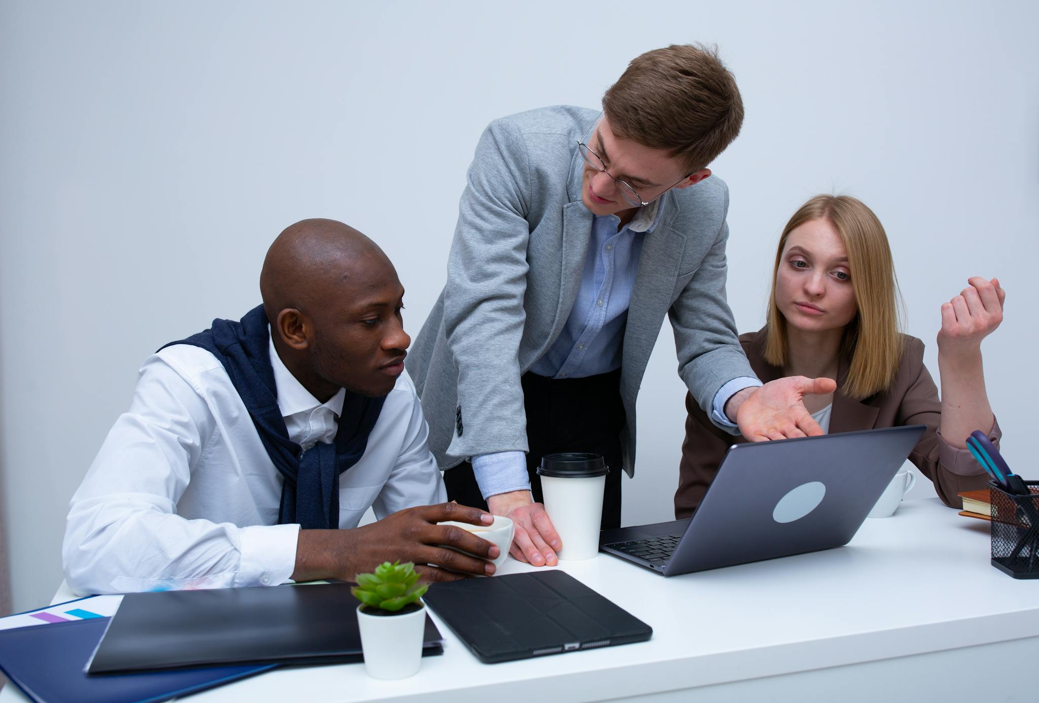 Three professionals engage in a lively business discussion at a modern office desk, focusing on teamwork.